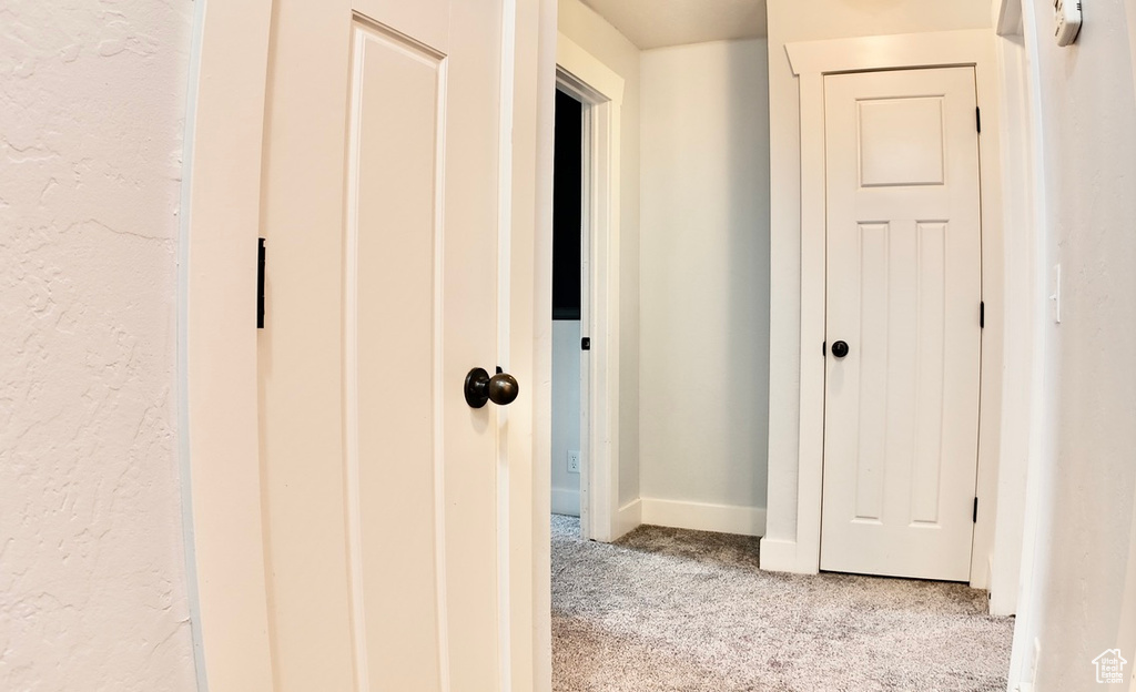 Hall featuring light carpet and baseboards