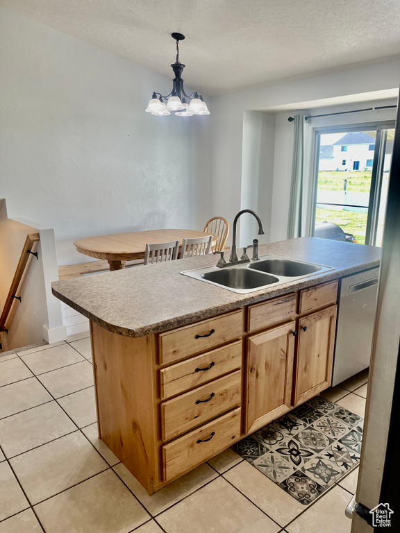 Kitchen featuring a sink, light brown cabinetry, dishwasher, light tile patterned floors, and a textured ceiling