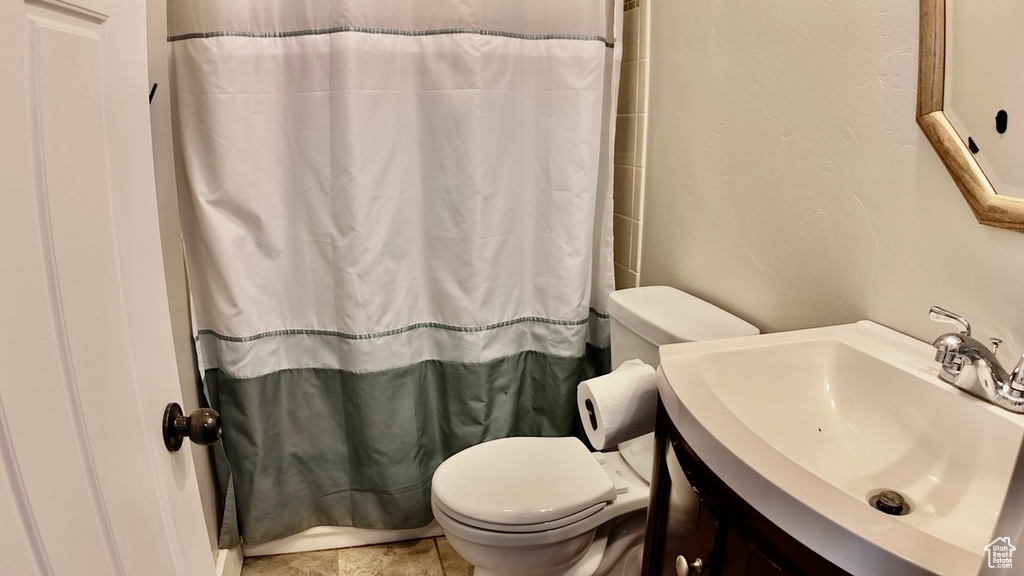 Bathroom featuring toilet, vanity, and curtained shower