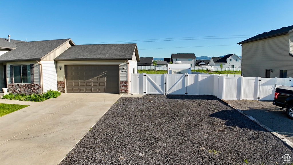 View of property exterior with a gate, a residential view, an attached garage, concrete driveway, and stone siding