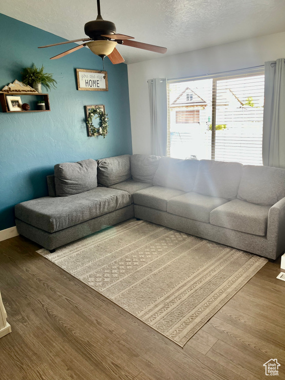 Living area featuring ceiling fan, wood finished floors, and a textured ceiling