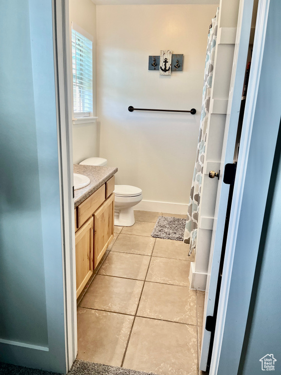 Bathroom with vanity, toilet, tile patterned floors, and a shower with shower curtain