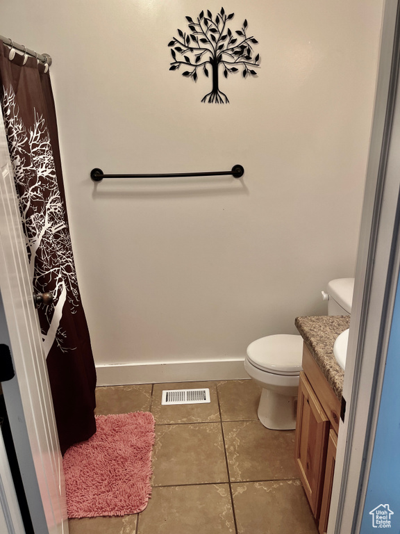 Bathroom featuring toilet, tile patterned flooring, vanity, and baseboards