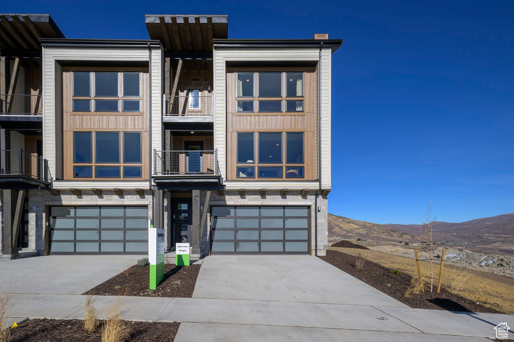 Contemporary home with a mountain view, a garage, driveway, and stone siding