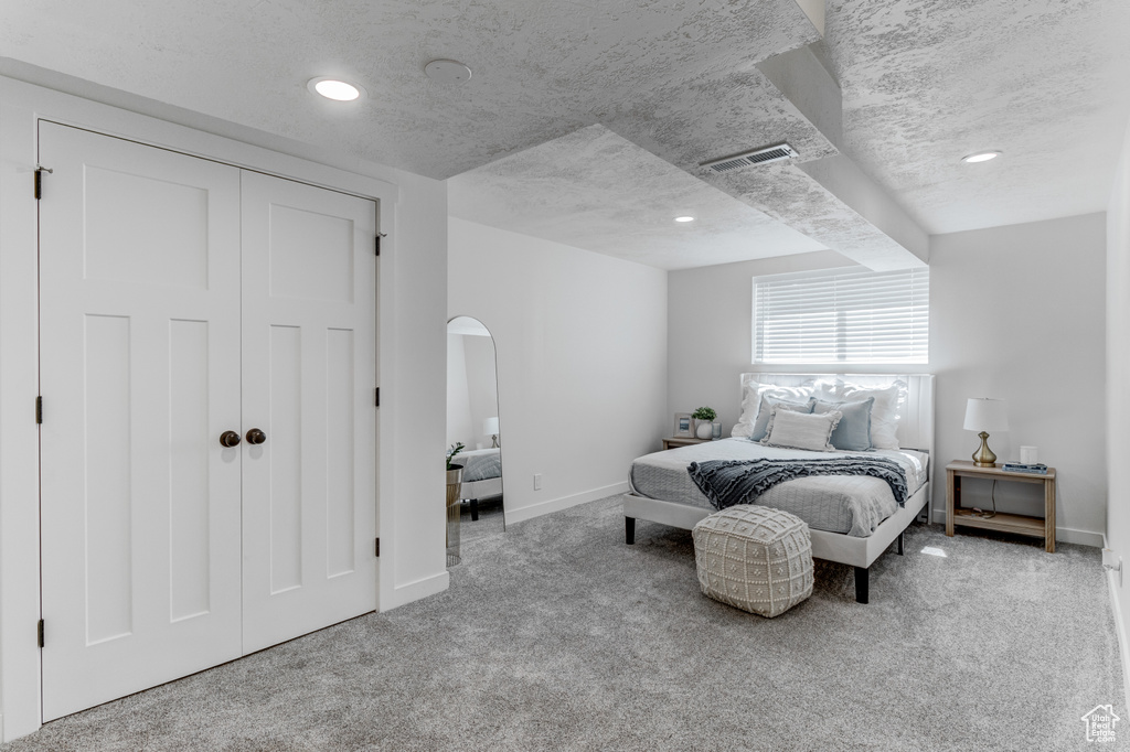 Bedroom with carpet, baseboards, arched walkways, a closet, and a textured ceiling
