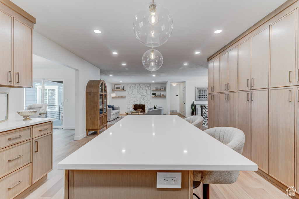 Kitchen featuring light brown cabinetry, open floor plan, a breakfast bar, recessed lighting, and light wood-type flooring