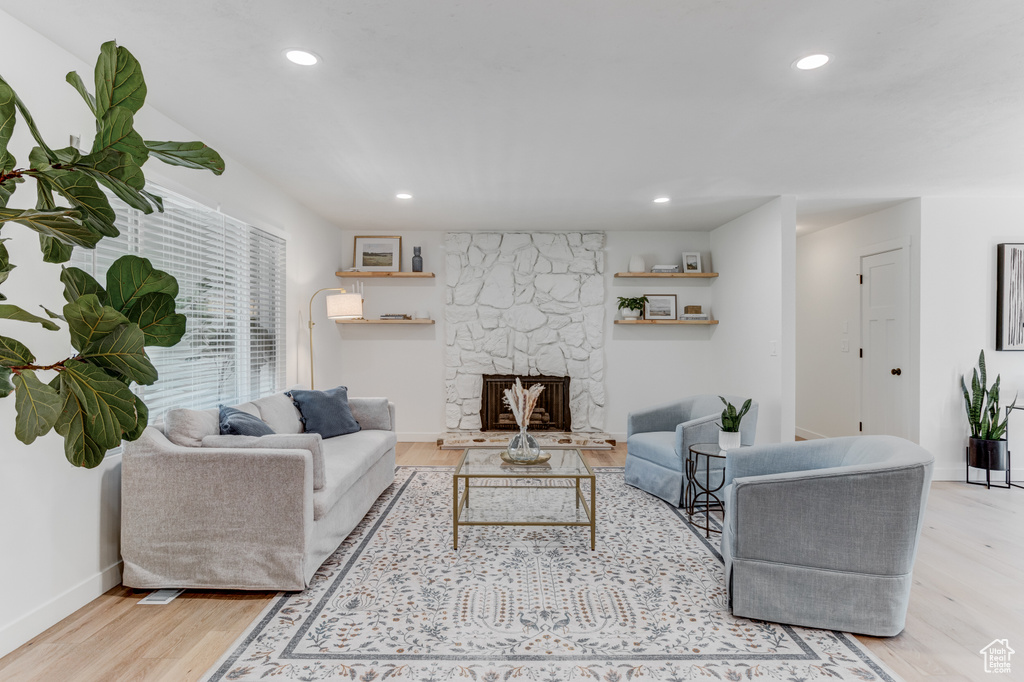 Living area featuring light wood finished floors, recessed lighting, baseboards, and a stone fireplace
