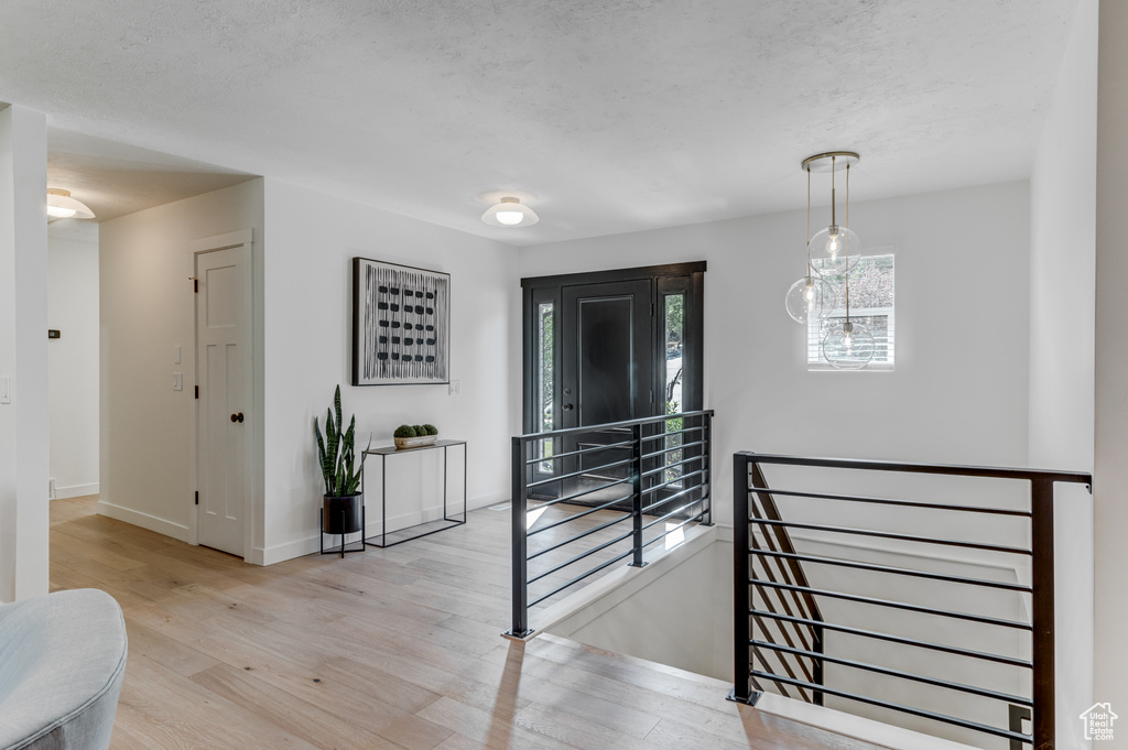 Corridor featuring an upstairs landing, wood finished floors, baseboards, and a textured ceiling