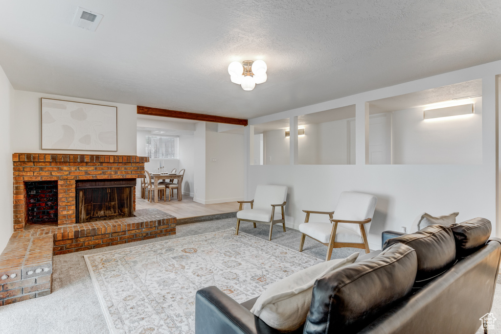 Carpeted living room with a fireplace, a textured ceiling, and baseboards