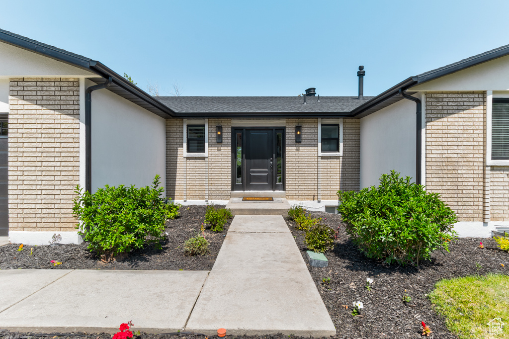 Doorway to property featuring brick siding and stucco siding