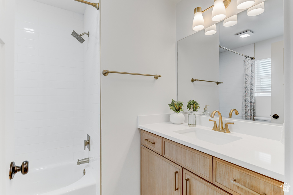 Bathroom featuring vanity and shower / bathtub combination with curtain