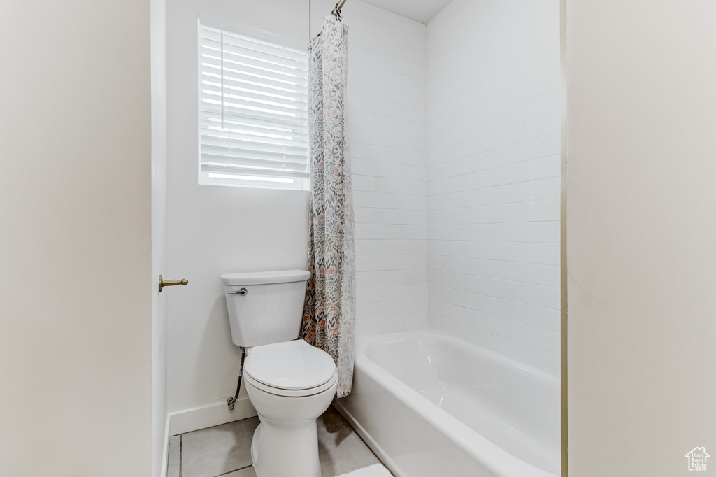 Full bathroom featuring toilet, shower / bathtub combination with curtain, baseboards, and tile patterned flooring