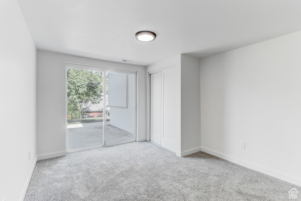 Unfurnished bedroom with access to outside, carpet, baseboards, and a closet