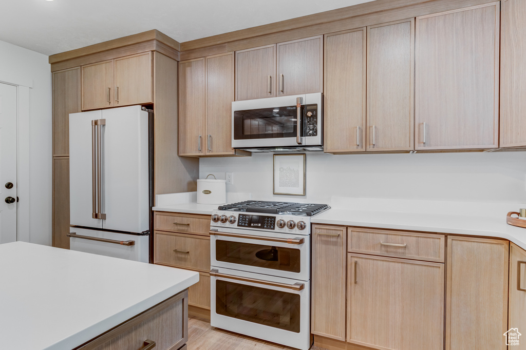 Kitchen featuring high quality appliances, light brown cabinetry, and light countertops