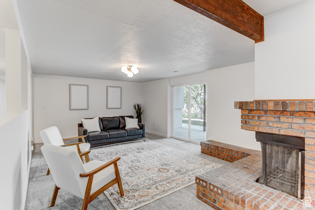 Living area with carpet floors, a fireplace, baseboards, and a textured ceiling