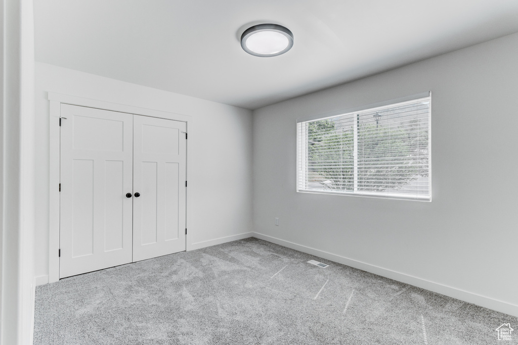 Unfurnished bedroom featuring carpet floors, baseboards, and a closet