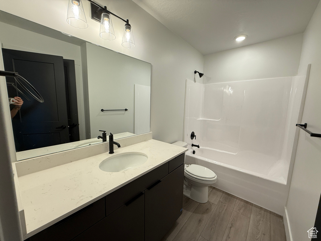 Full bath featuring vanity, shower / bathtub combination, wood finished floors, and toilet