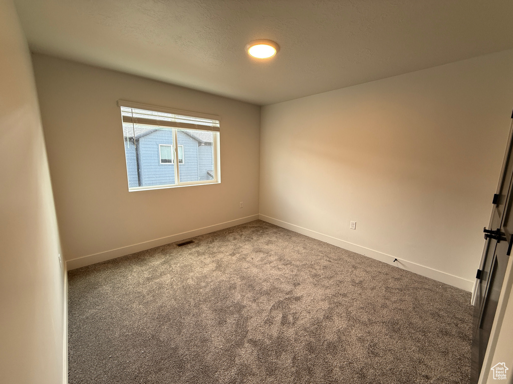 Carpeted empty room featuring baseboards and visible vents