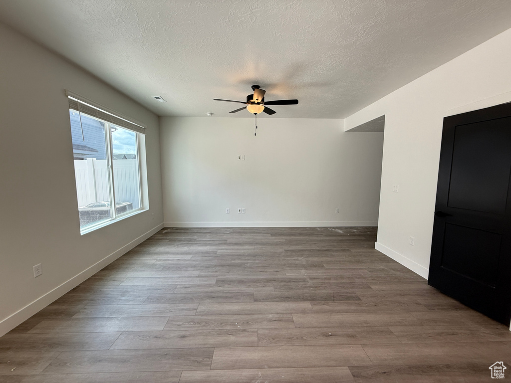 Spare room featuring baseboards, a ceiling fan, a textured ceiling, and wood finished floors