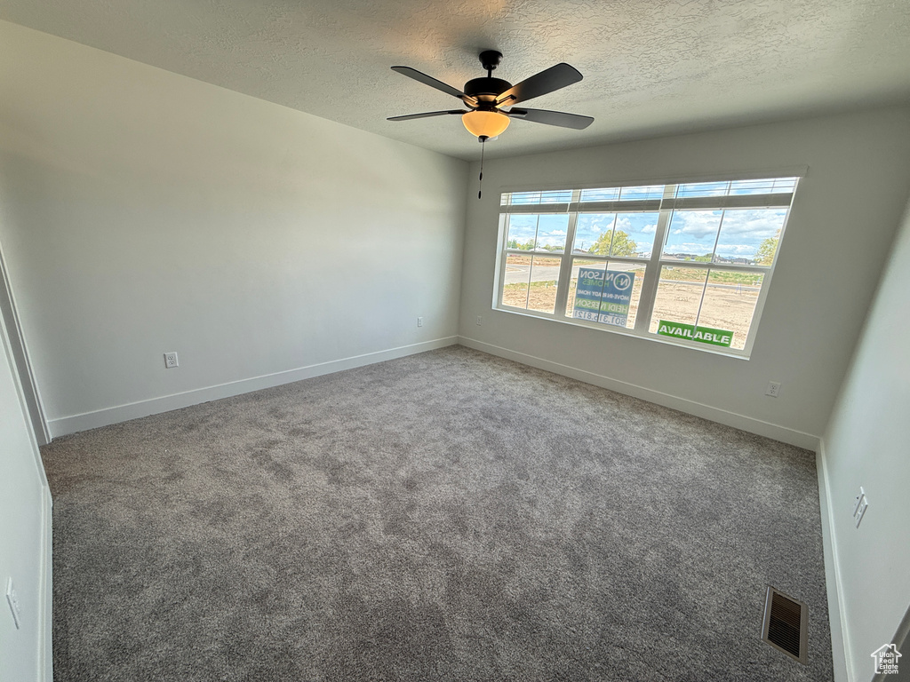Unfurnished room featuring ceiling fan, a textured ceiling, visible vents, baseboards, and carpet flooring