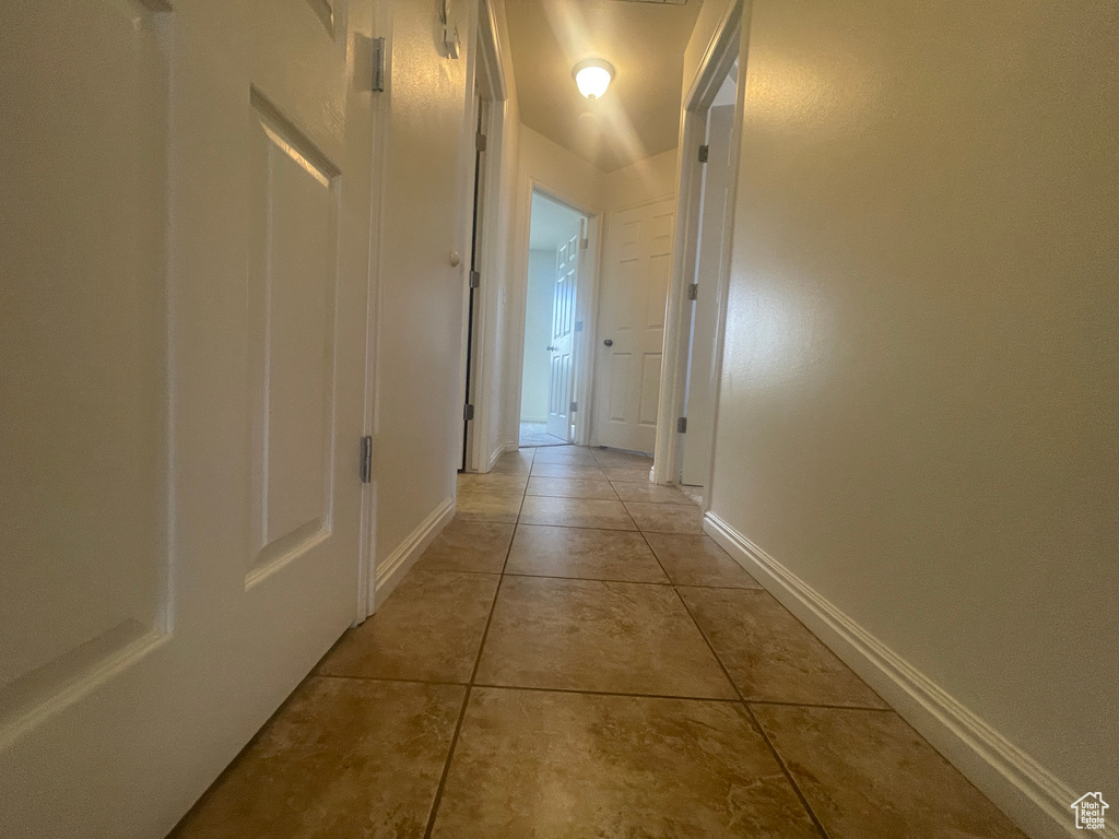 Hallway with light tile patterned floors and baseboards