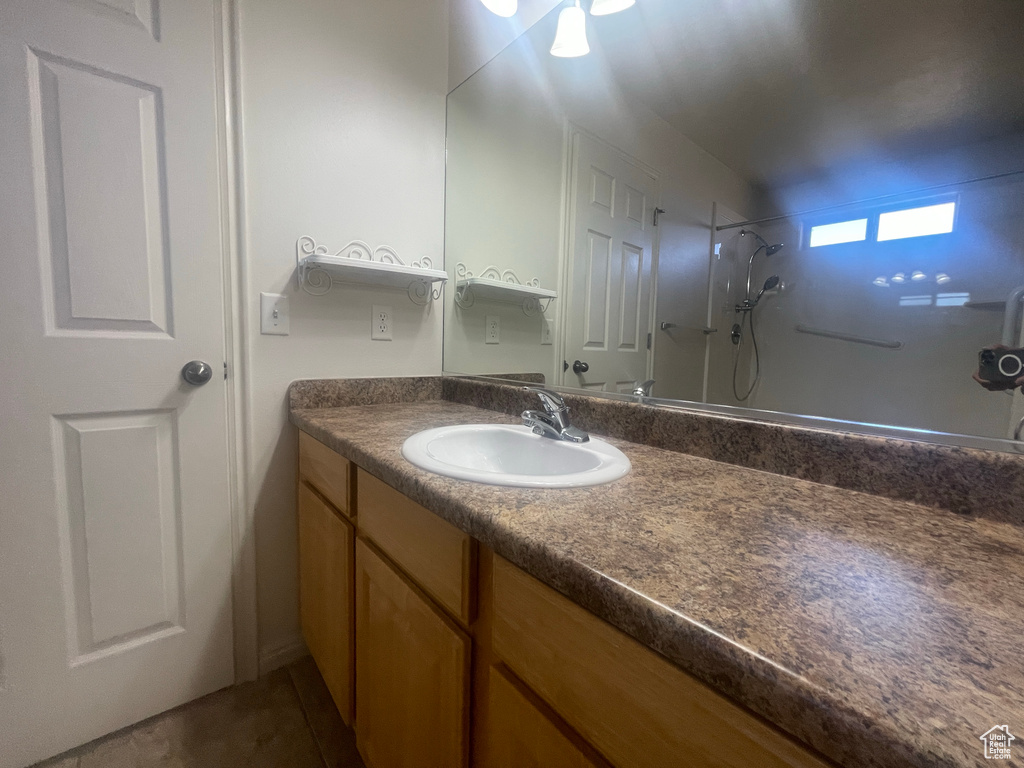 Full bath featuring vanity, a shower, and tile patterned flooring