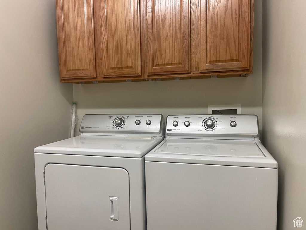 Washroom featuring independent washer and dryer and cabinet space