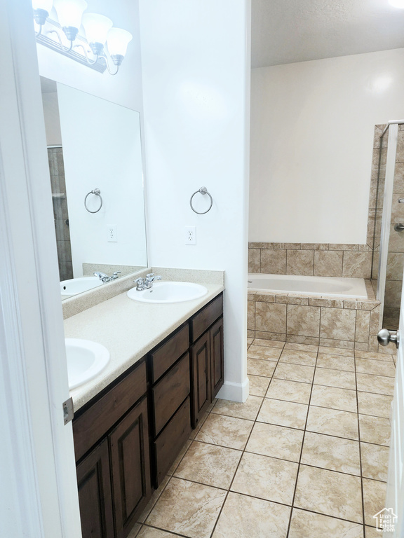 Bathroom with double vanity, a relaxing tiled tub, and tile patterned floors