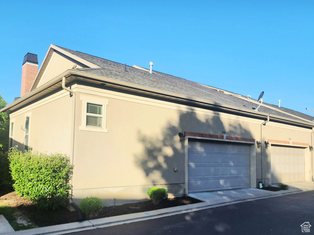 View of home\'s exterior with stucco siding, a chimney, and a shingled roof