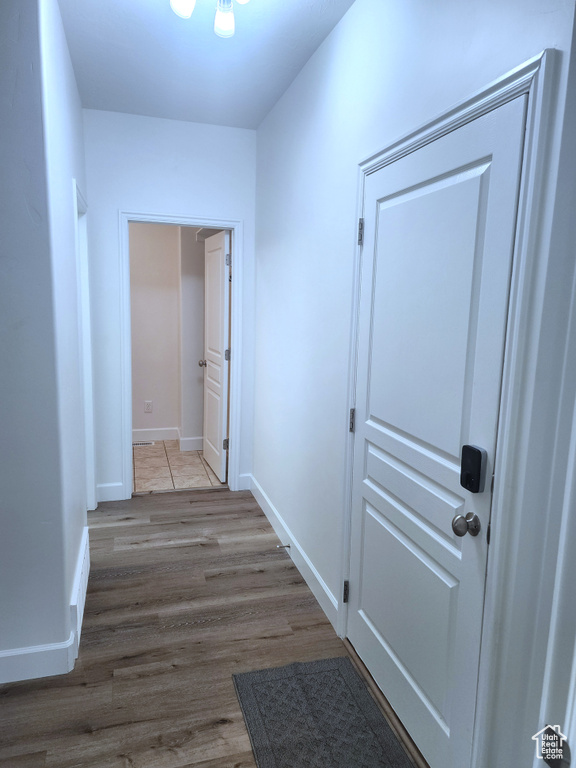Hallway featuring wood finished floors, baseboards, and a chandelier