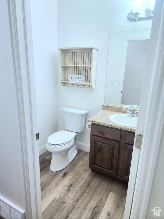 Bathroom with vanity, toilet, wood finished floors, and baseboards
