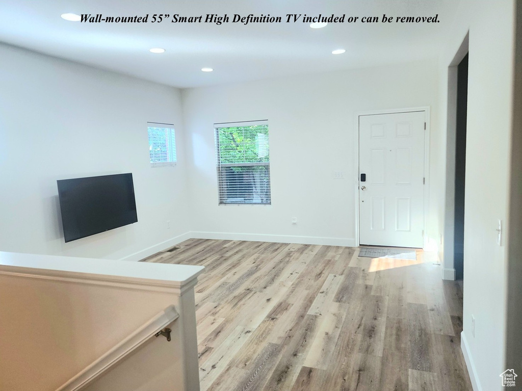 Unfurnished living room with light wood finished floors, recessed lighting, and baseboards
