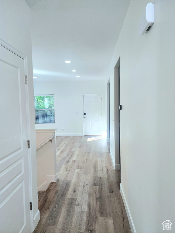 Hall with wood finished floors, baseboards, recessed lighting, and an upstairs landing