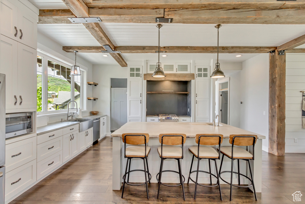 Kitchen with a sink, stainless steel appliances, beam ceiling, dark wood finished floors, and white cabinets