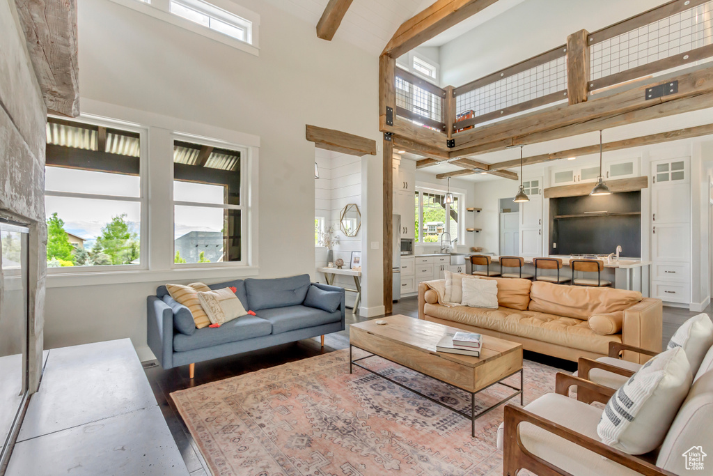 Living area with a high ceiling, beam ceiling, wood finished floors, and baseboards