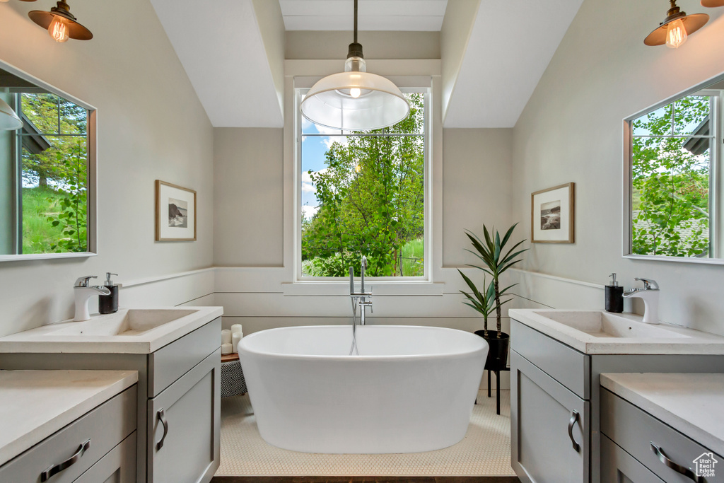 Full bathroom with two vanities, a freestanding tub, and healthy amount of natural light