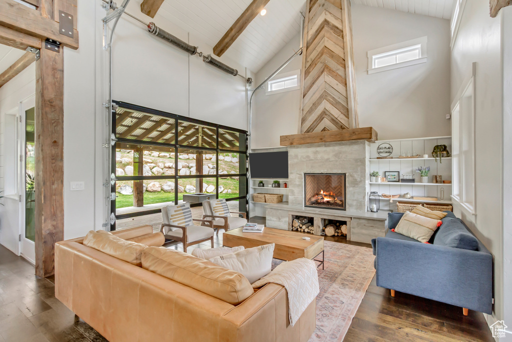 Living area with high vaulted ceiling, wood-type flooring, a tile fireplace, plenty of natural light, and beamed ceiling