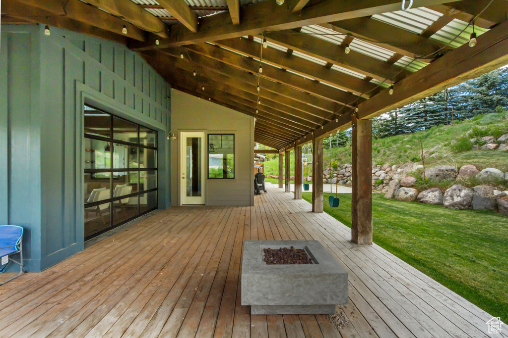 Wooden terrace with an outdoor fire pit and a yard