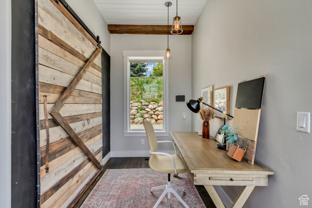 Office space with a barn door, dark wood-type flooring, and baseboards