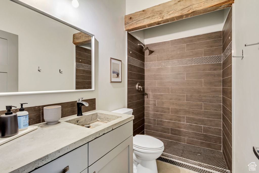 Bathroom with toilet, a tile shower, and vanity