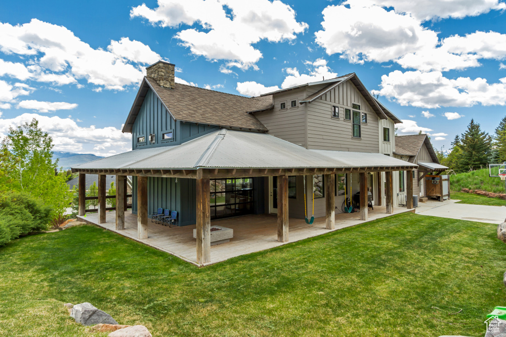 Rear view of house with board and batten siding, a patio, and a yard