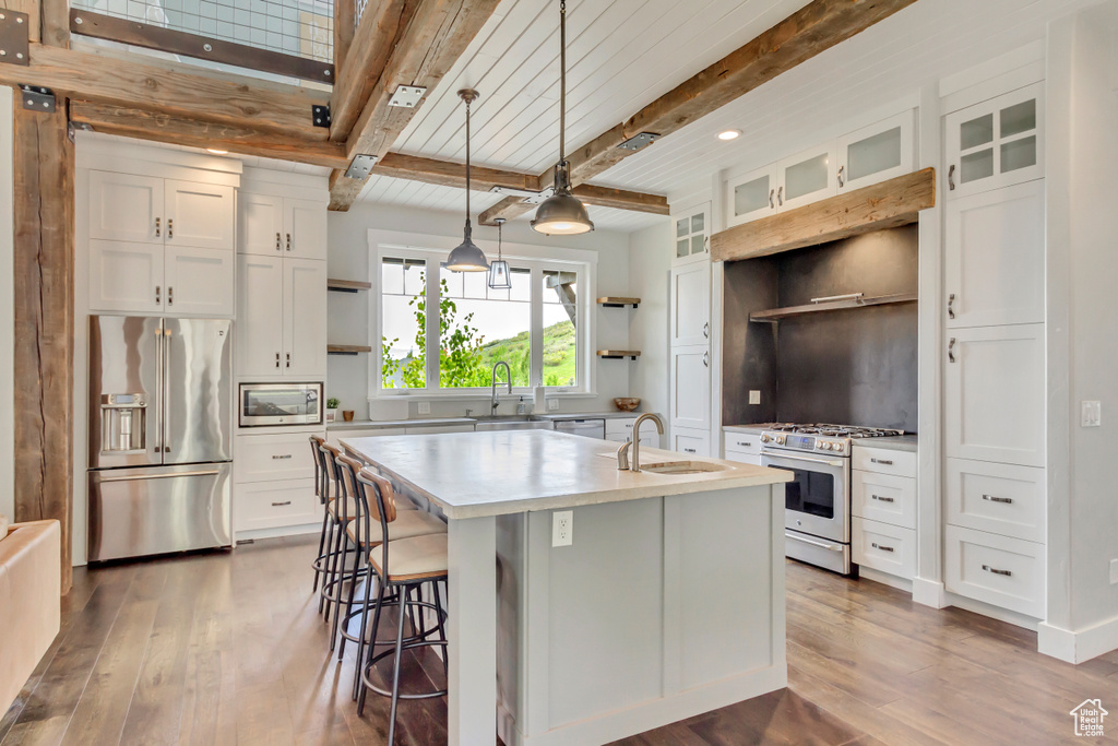Kitchen with premium appliances, open shelves, a sink, wood-type flooring, and beamed ceiling