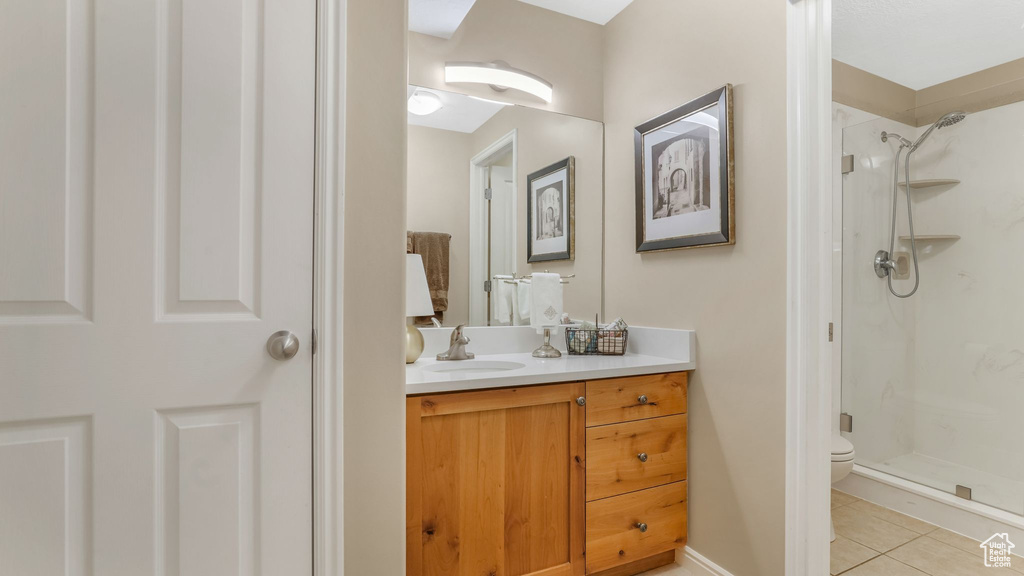 Bathroom featuring a stall shower, vanity, tile patterned flooring, and toilet