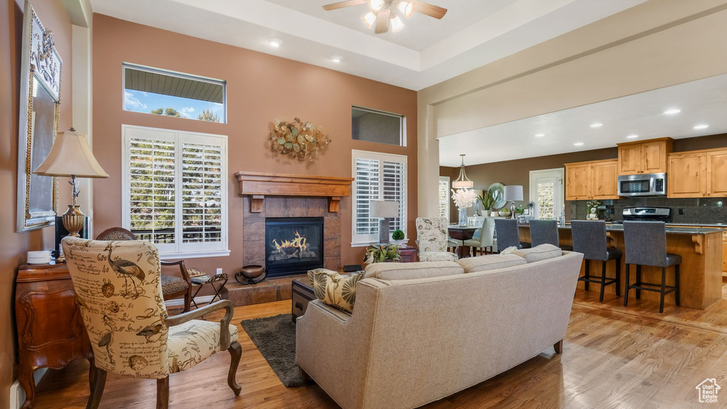 Living room featuring plenty of natural light, a tiled fireplace, ceiling fan, light wood finished floors, and recessed lighting