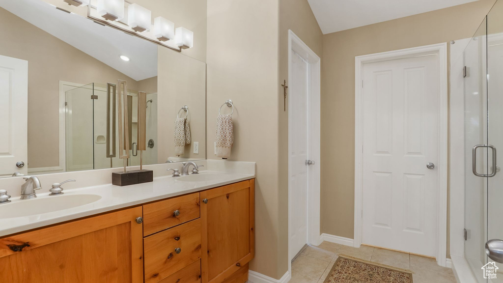 Full bathroom with double vanity, a stall shower, tile patterned flooring, a closet, and baseboards