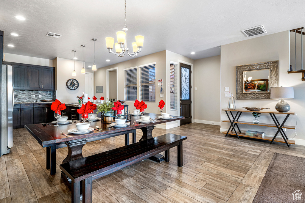 Dining room with light wood-type flooring, baseboards, recessed lighting, and a chandelier