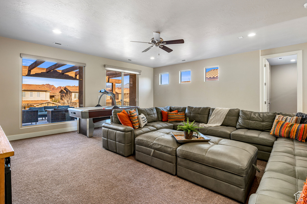 Carpeted living area featuring ceiling fan and recessed lighting