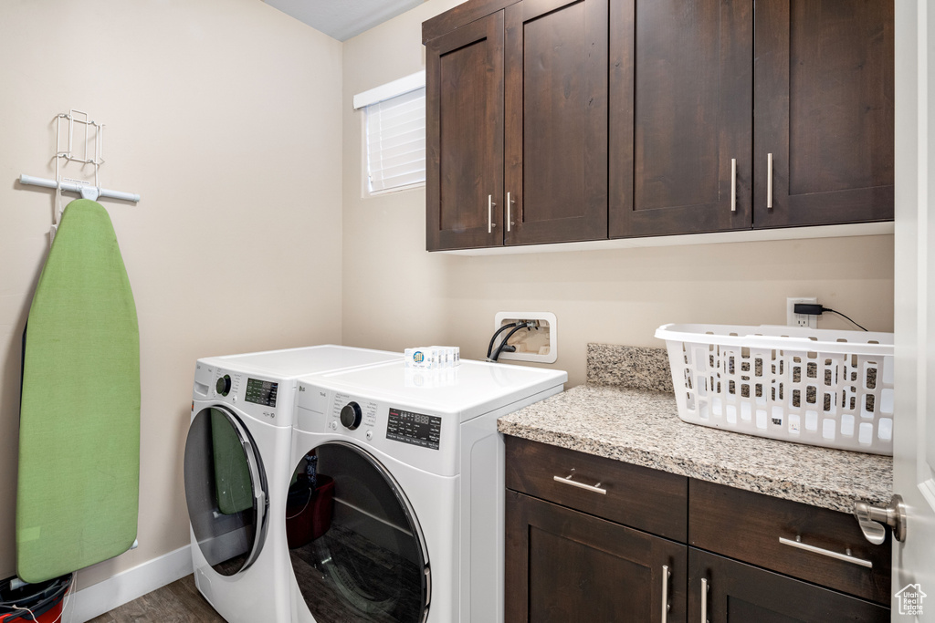 Laundry area with cabinet space, separate washer and dryer, baseboards, and wood finished floors