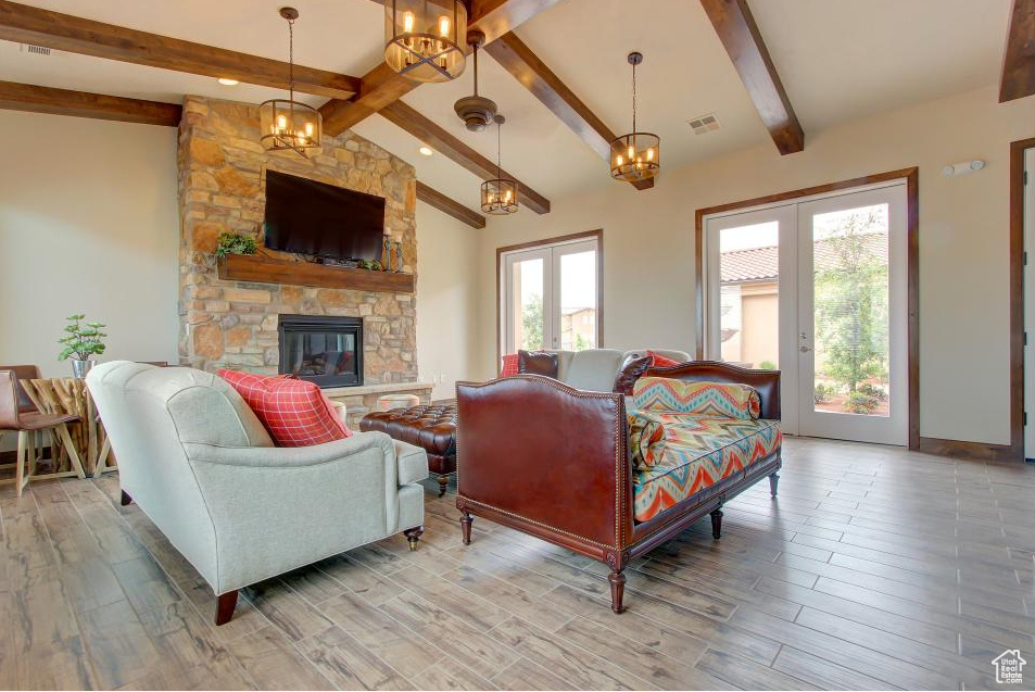 Living room featuring light wood finished floors, a fireplace, a chandelier, and french doors