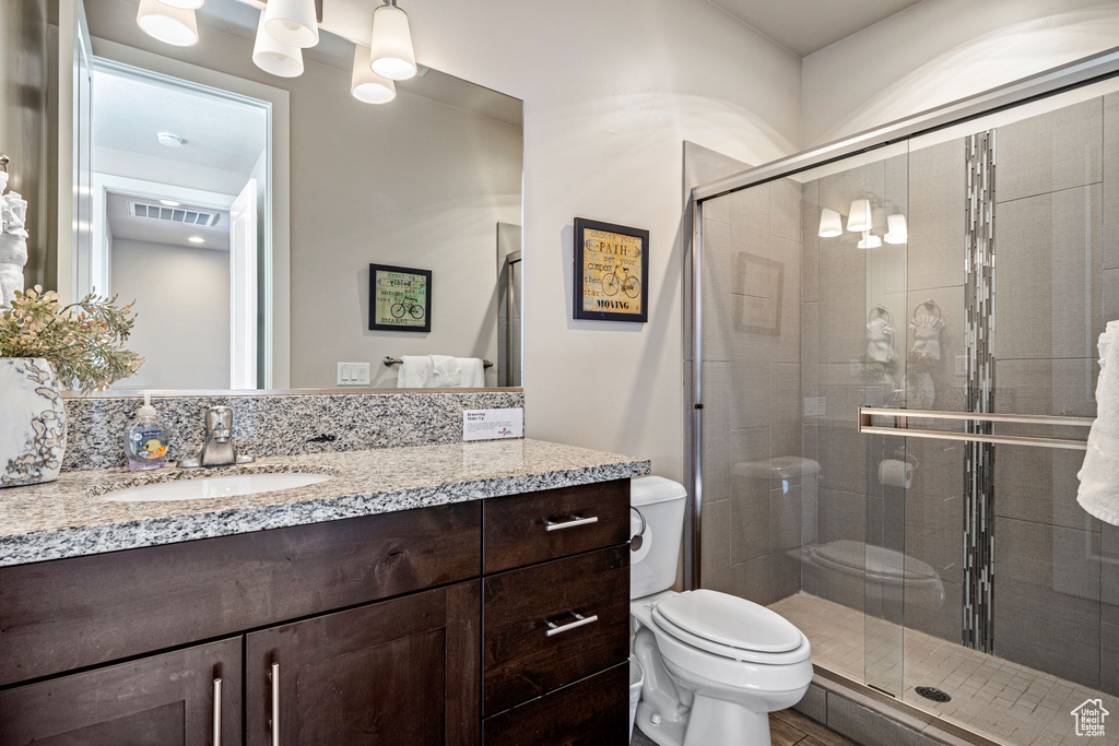 Bathroom featuring a shower stall, toilet, and vanity